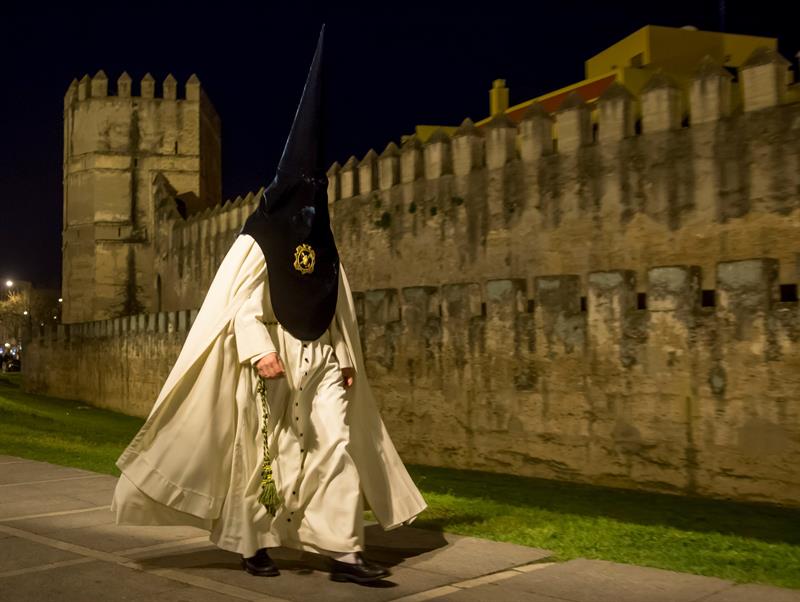 Un nazareno de la Hermandad de La Macarena se dirige al Templo para efectuar su estación de Penitencia en la Madrugá, la noche grande de la Semana Santa de Sevilla.