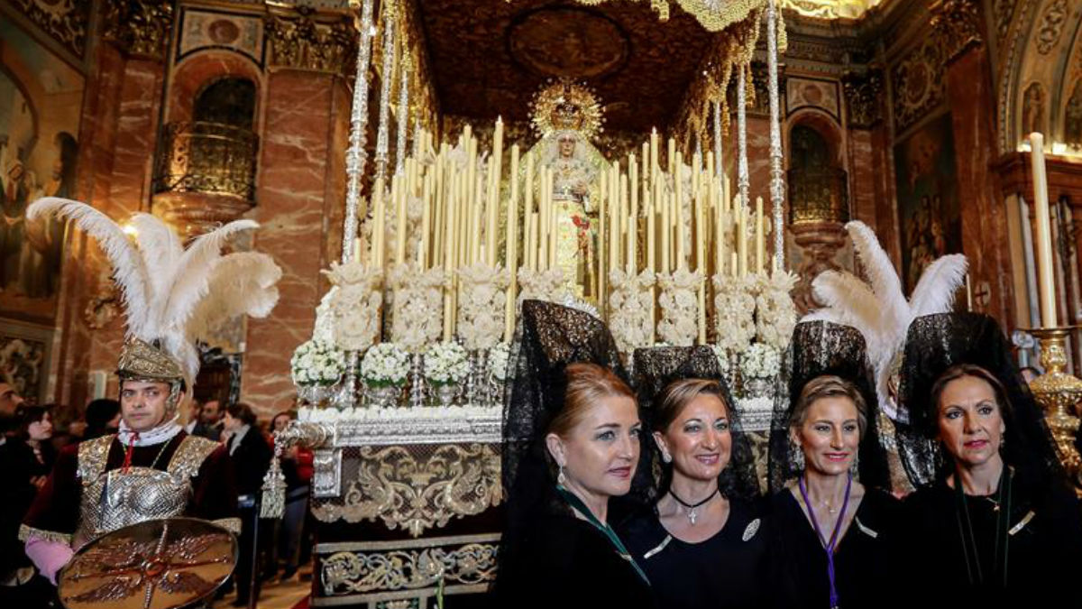 Un grupo de mujeres vestidas de mantilla se fotografían ante la Virgen de la Macarena, antes de salir en procesión en la Madrugá sevillana. Foto: EFE