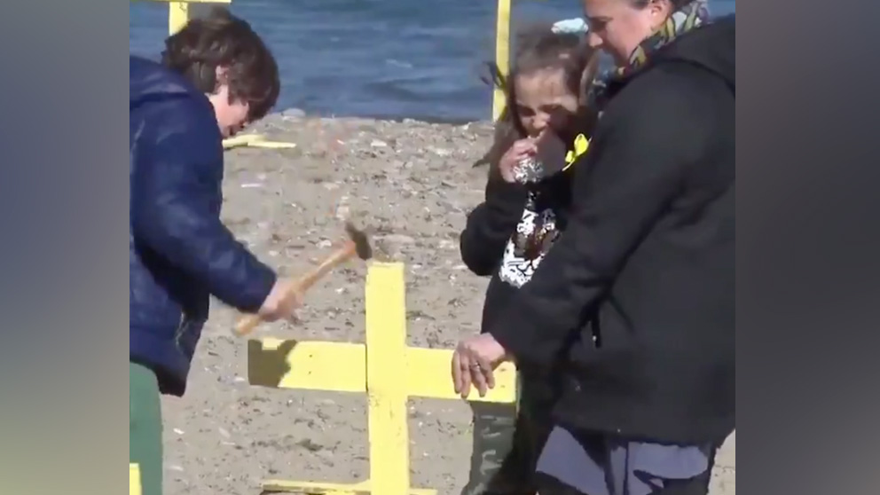 Menores clavando cruces amarillas en una playa de Gerona