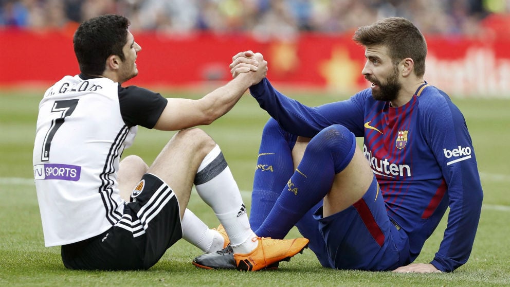 Piqué y Guedes se ayudan a levantarse del suelo. (EFE)