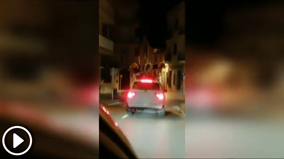Dos chicas bailan sobre un coche en marcha con matrícula alemana en las calle de Jávea (Alicante).