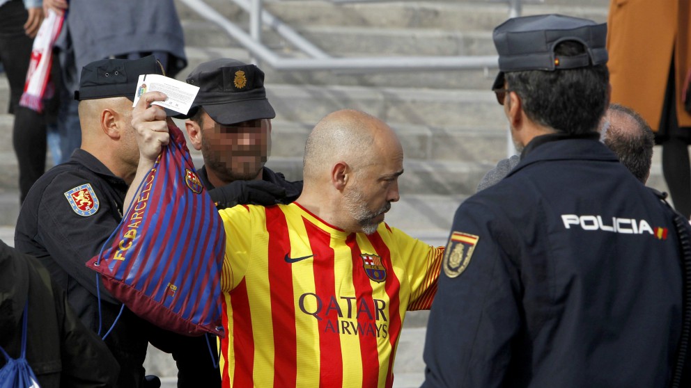 Miembros de la Policía cachean a un aficionado del Barcelona. (EFE)