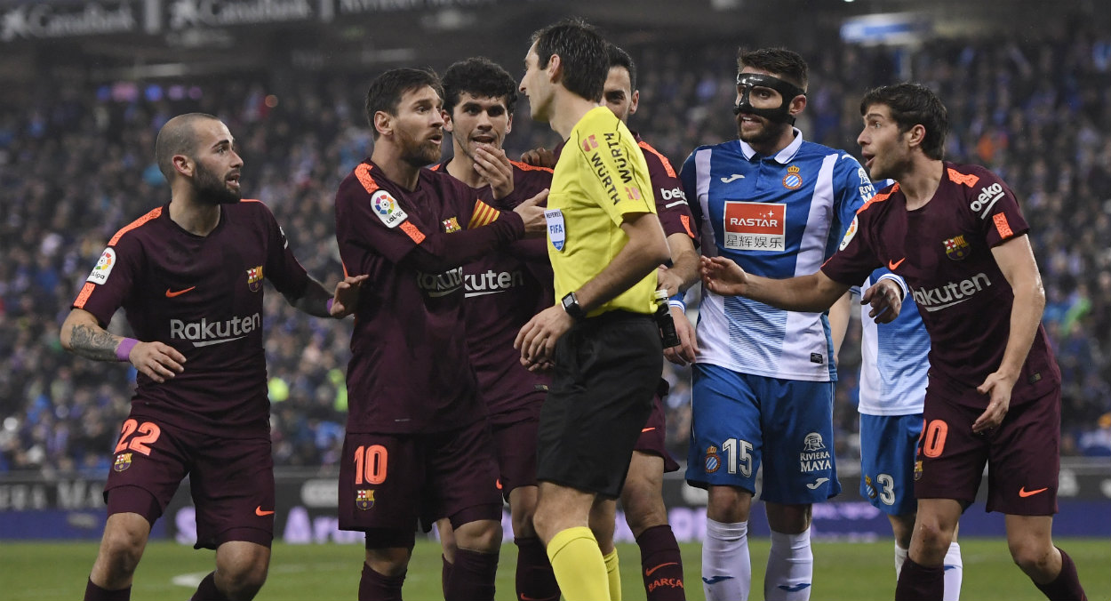 Los jugadores del Barcelona presionan al árbitro en un partido contra el Espanyol. (AFP)