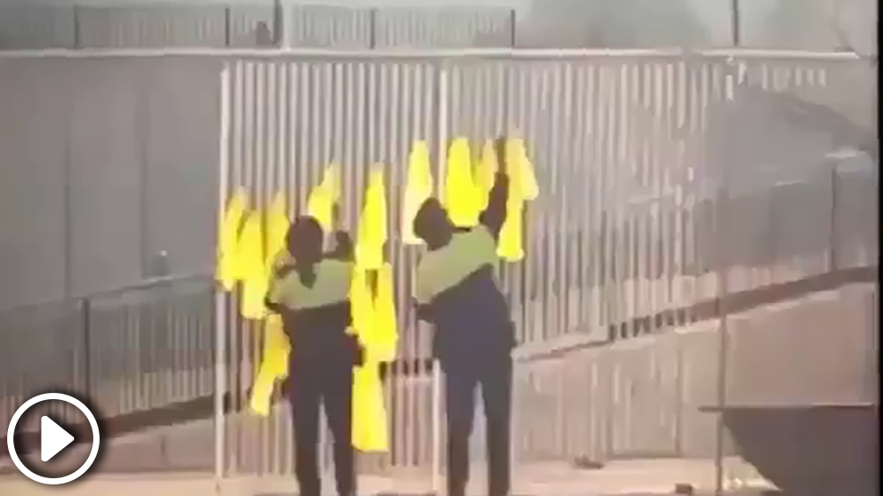 Dos agentes de los Mossos quitando lazos amarillos de un colegio público