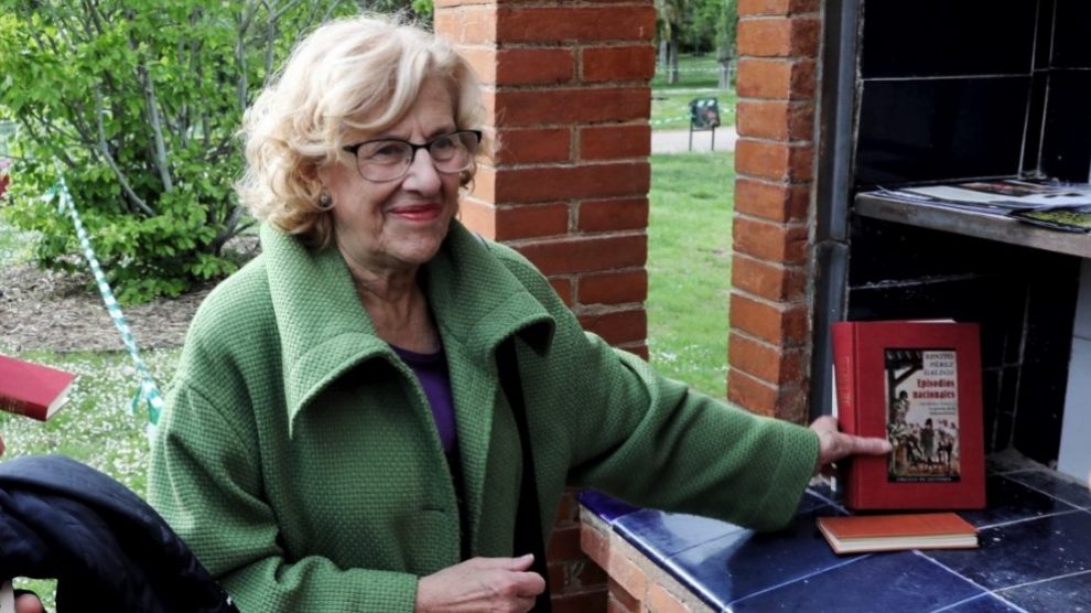 Manuela Carmena cogiendo un libro en El Retiro. (Foto. Madrid)