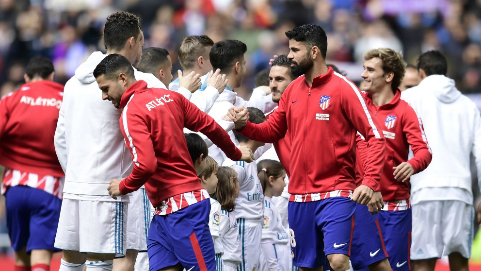 Los jugadores de Real Madrid y Atlético de Madrid se saludan antes de un derbi. (AFP)