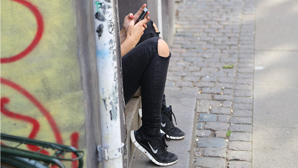 Una adolescente consulta las redes sociales en su teléfono móvil.