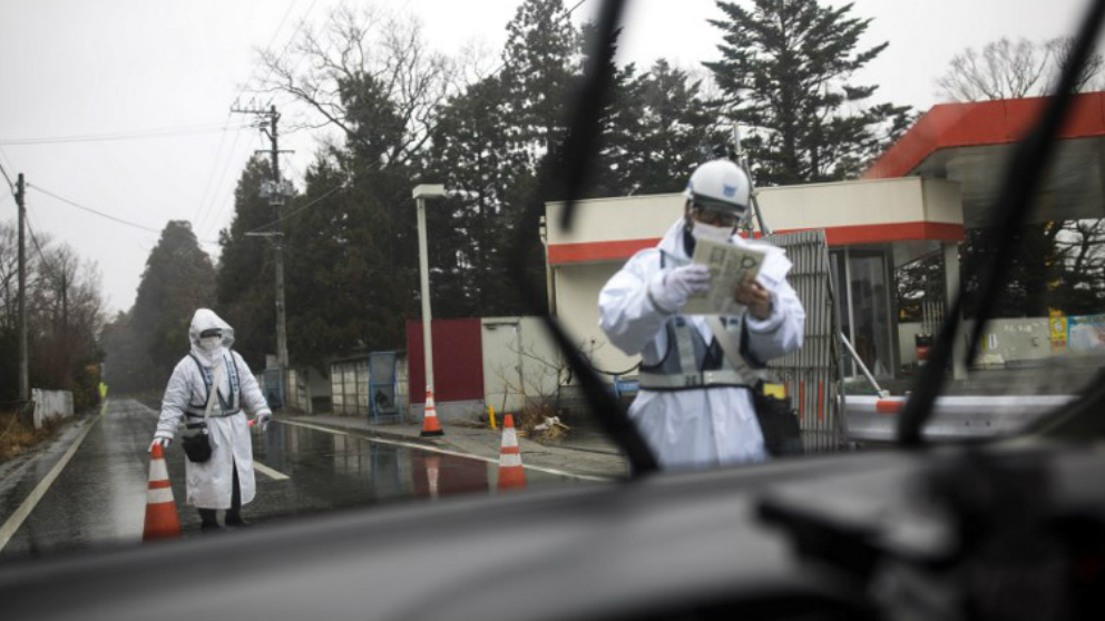 Dos agentes conprueban la documentación de un vehículo que quiere entrar en la zona de Fukushima. Foto: AFP