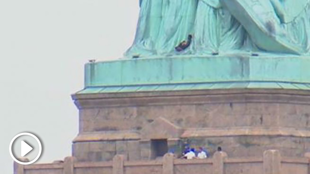 Una mujer escala la Estatua de la Libertad.