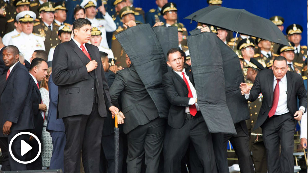 Los escoltas despliegan un escudo antibalas para proteger a Maduro durante el desfile.