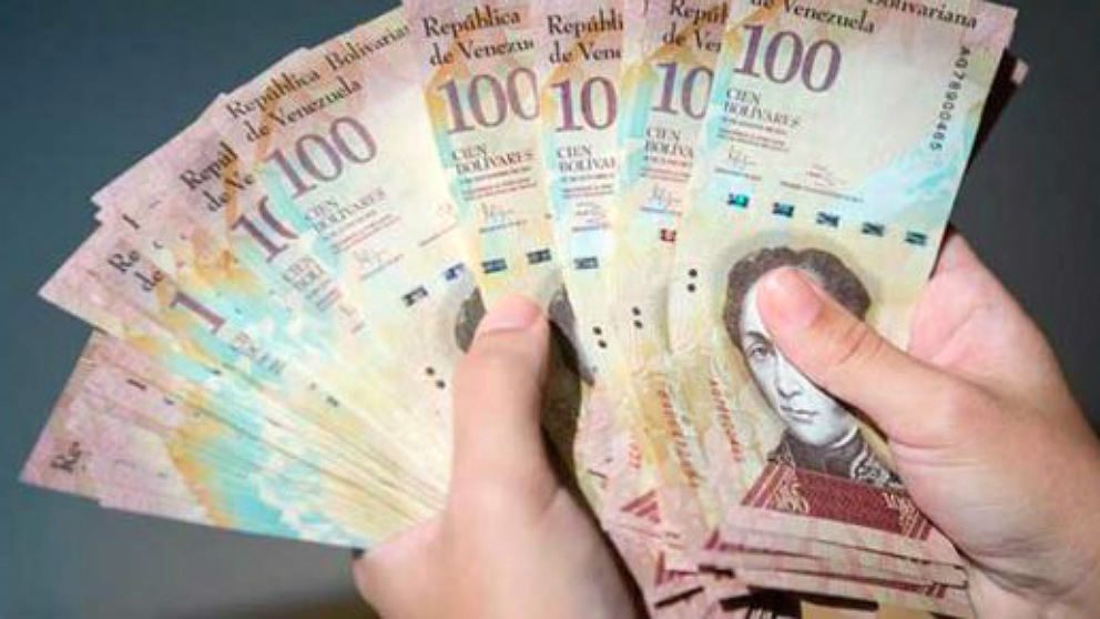Un venezolano cuenta un enorme fajo de billetes de 100 bolívares. (ENP)