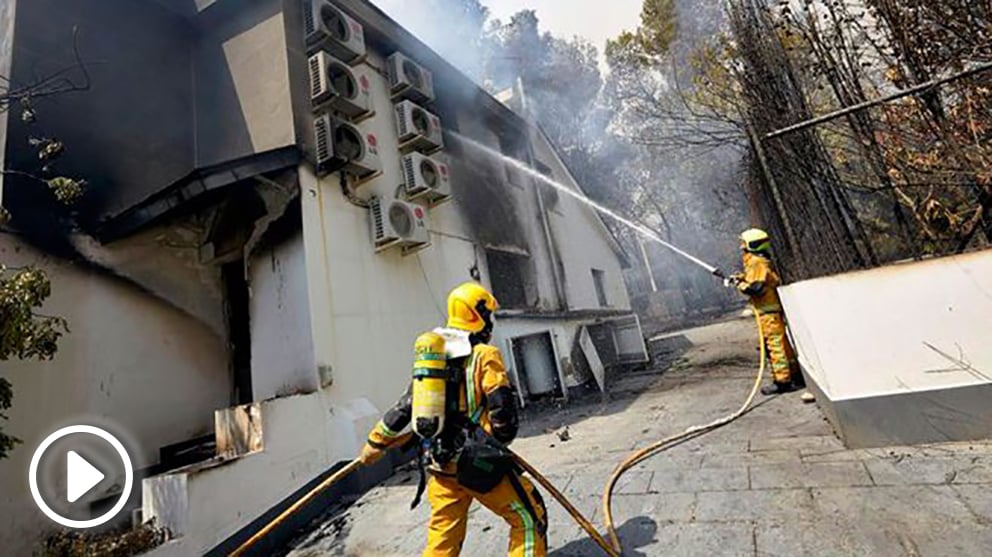 Dos bomberos refrescan en interior de una de las viviendas afectadas por el incendio forestal de Llutxent en la zona de la Marxuqera (Gandía). Foto: EFE
