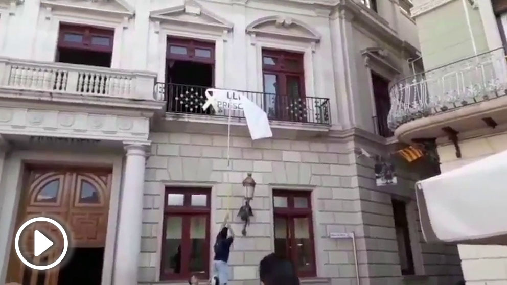 Militantes de Ciudadanos retiran la propaganda independentista de la fachada del Ayuntamiento de Reus.