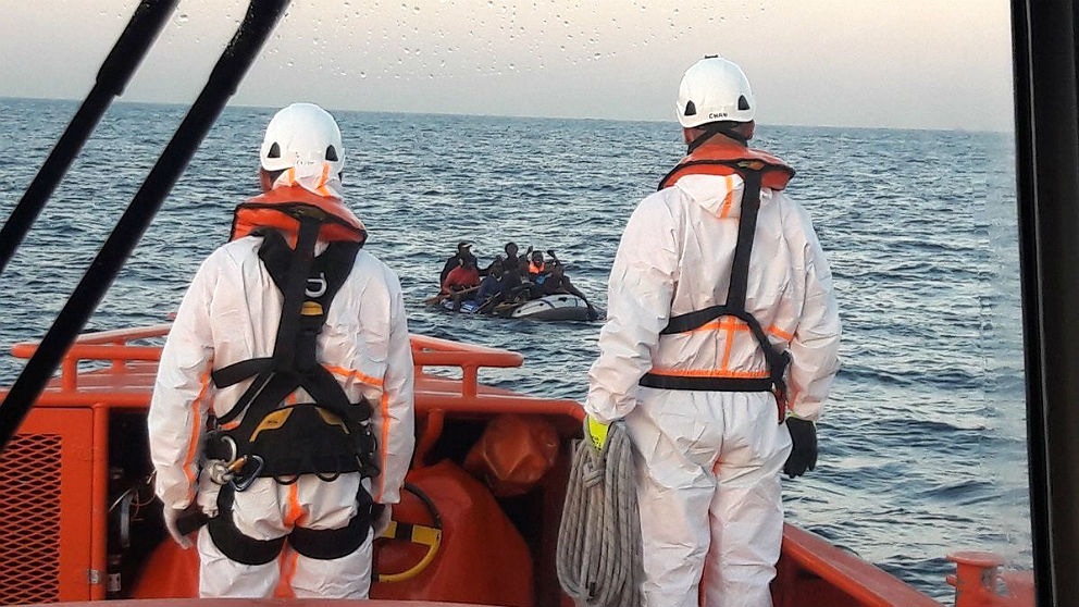 Dos trabajadores de Salvamento Marítimo rescatan una lancha con inmigrantes subsaharianos. (EP)s
