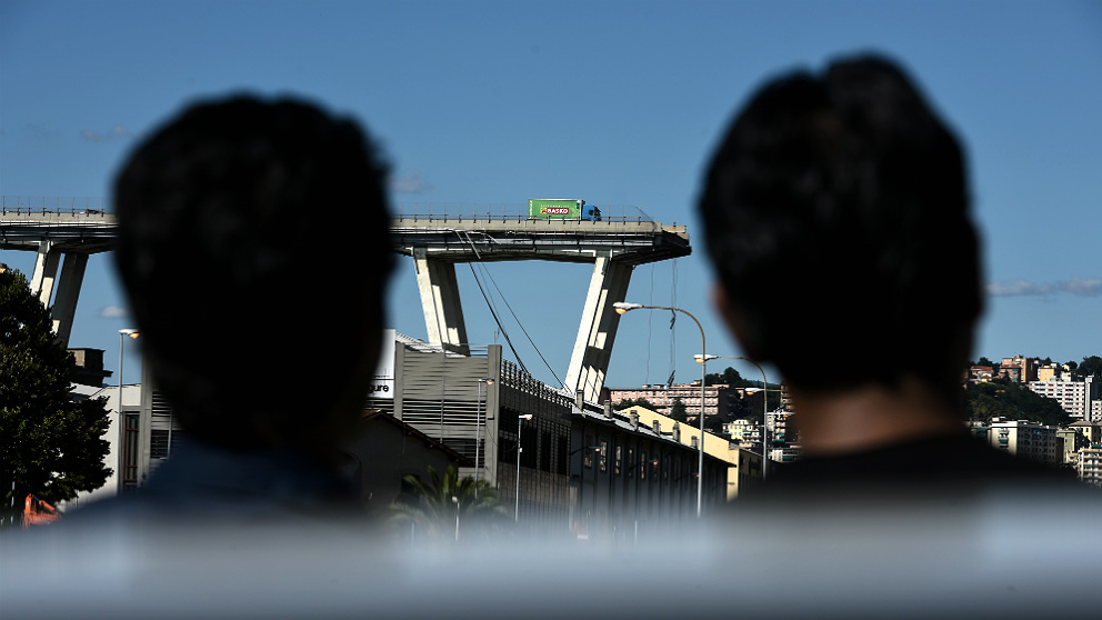 Dos vecinos observan desde lejos la sección caída del viaducto de Génova. (AFP)