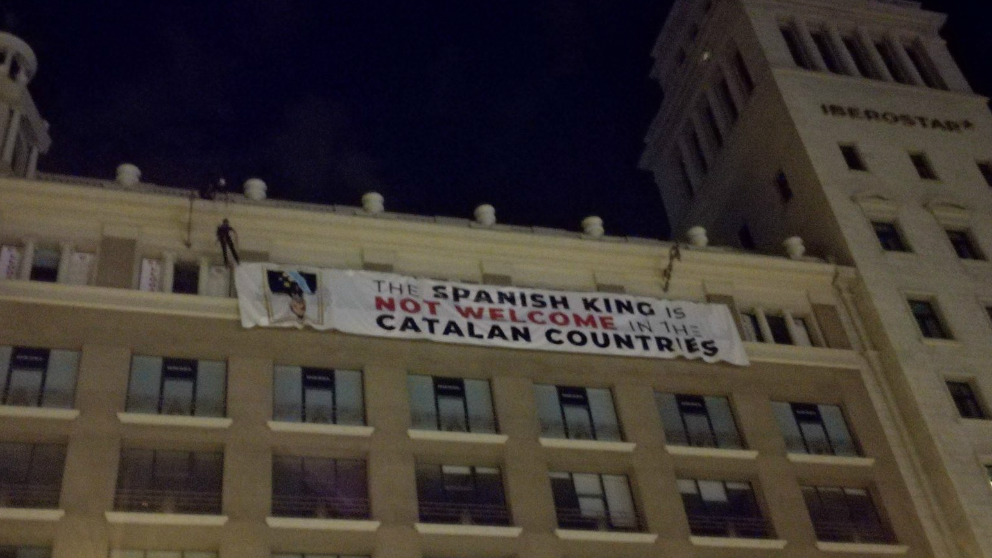 Un grupo de Mossos d’Esquadra se descuelga por la fachada de un edificio en Plaza Cataluña de Barcelona para descolgar una pancarta contra el Rey Felipe VI.