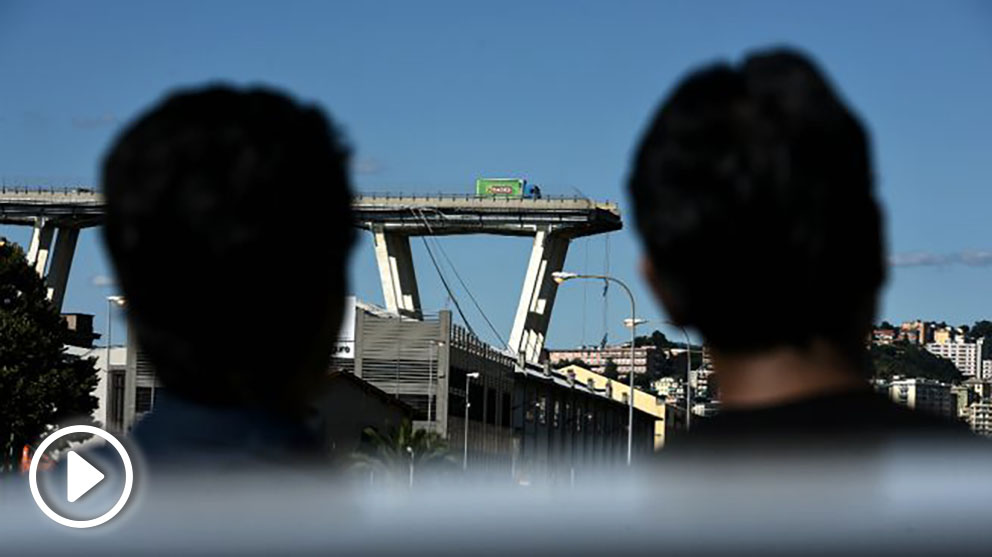 Dos vecinos observan desde lejos la sección caída del viaducto de Génova. (AFP)