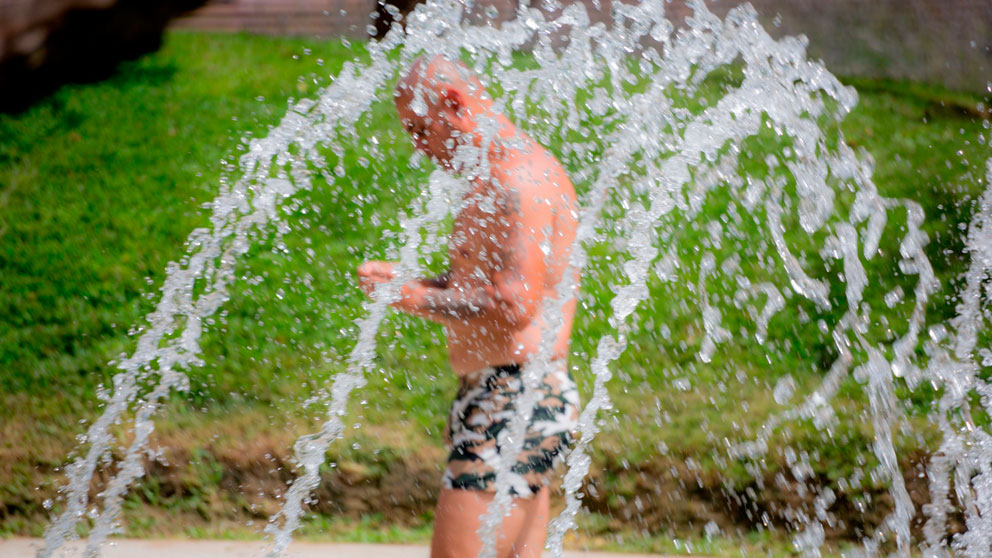 Un hombre palia los efectos de las altas temperaturas refrescándose en el agua. Foto: Europa PRess