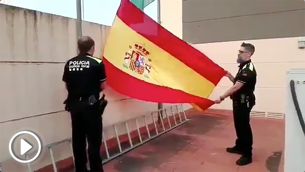 Policías locales de Abrera (Barcelona) izan la bandera de España  al son del himno nacional.