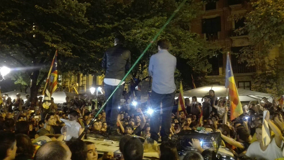 Jordi Sànchez y Jordi Cuixart, subidos a un coche de la Guardia Civil, durante el asedio del 20-S a la comisión judicial en la Consejería de Economía de la Generalitat. (EP)