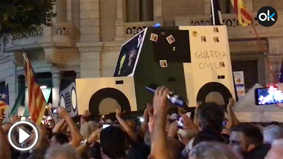 Manifestantes con una réplica de cartón de uno de los coches de la Guardia Civil destrozados hace un año.