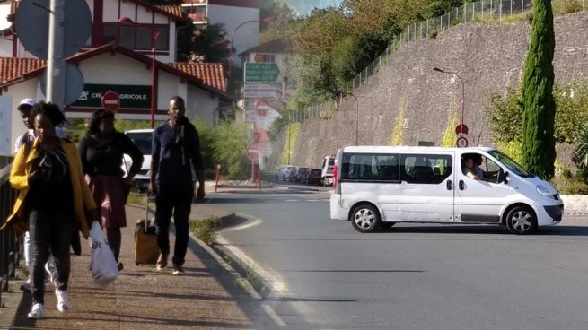 Un grupo de inmigrantes irregulares cruzan la frontera tras ser trasladados en una furgoneta de la policía francesa sin indicativos.