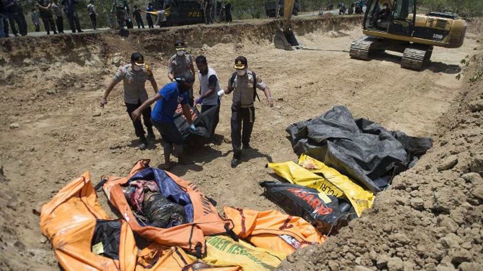 Voluntarios trasladas cadáveres a una fosa común donde se entierran a los muertos para evitar la propagación de enfermedades. Foto: AFP