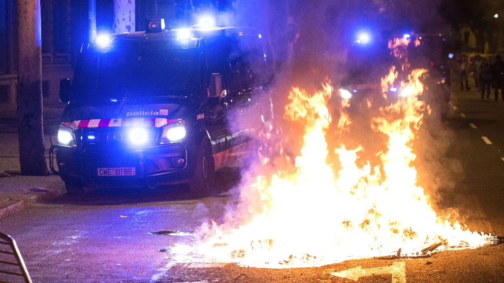 Un furgón de los Mossos pasa junto al fuego durante los altercados al finalizar la movilización convocada por la ANC y otras entidades independentistas con motivo del primer aniversario del 1-O (Foto: Efe)