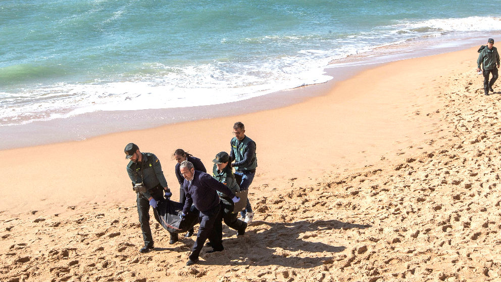 Agentes de la Guardia Civil trasladan el cadáver de un inmigrante (Foto: EFE).