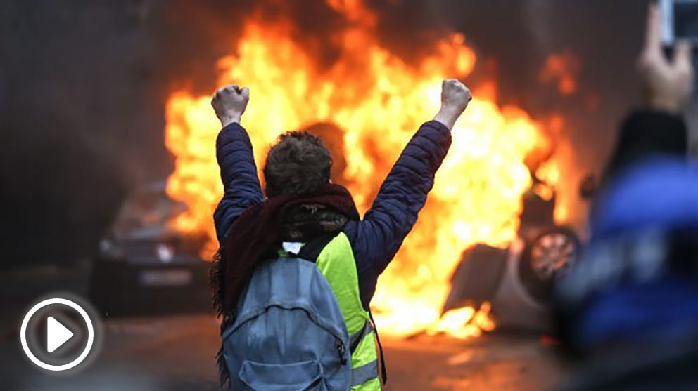 Un manifestante ante un vehículo incendiado (Foto: AFP).
