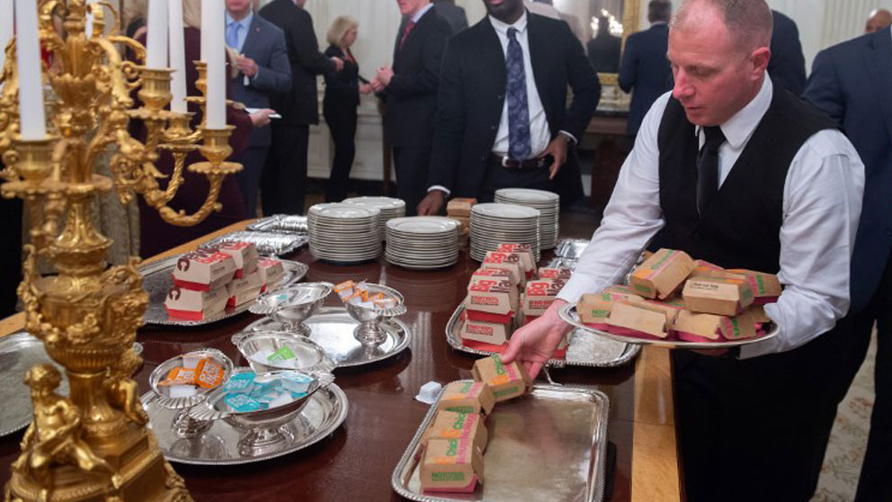un camarero de La Casa Blanca coloca los alimentos de McDonalds en las bandejas de plata del salón de recepciones. Foto: AFP