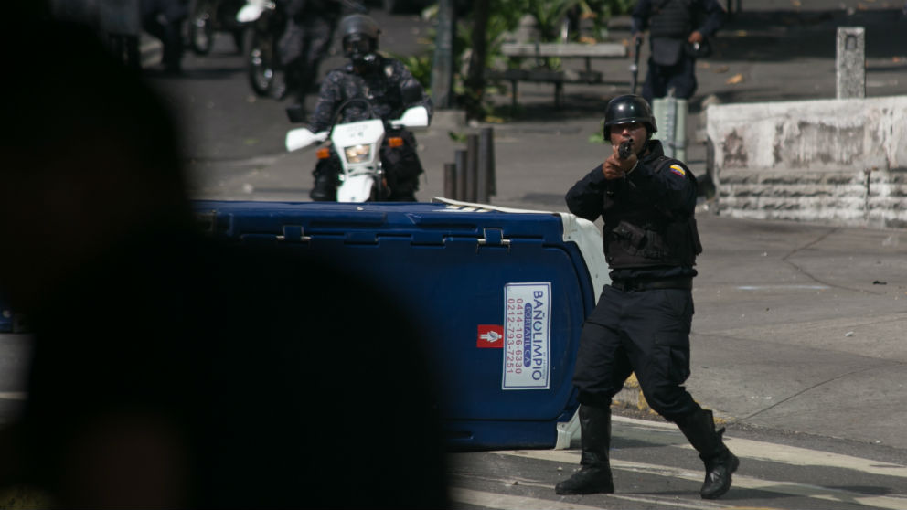 Un policía de Maduro apunta su arma contra manifestantes a favor del presidente legítimo Guaidó. (Foto: EP)