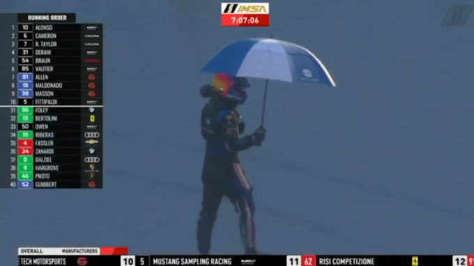 Fernando Alonso, tras salir del Cadillac paraguas en mano.