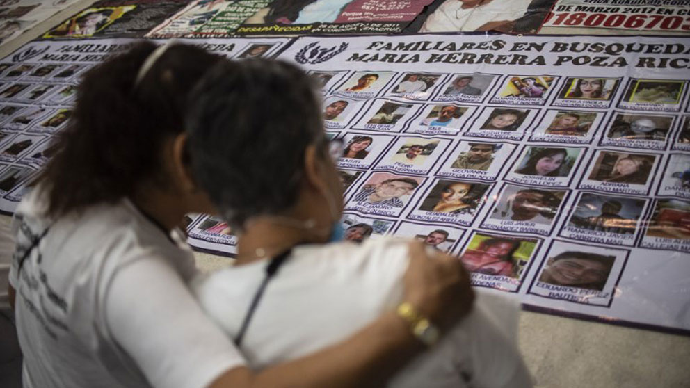 Madre e hija buscan en un mural las fotos de sus familiares desaparecidos en México. Foto: AFP