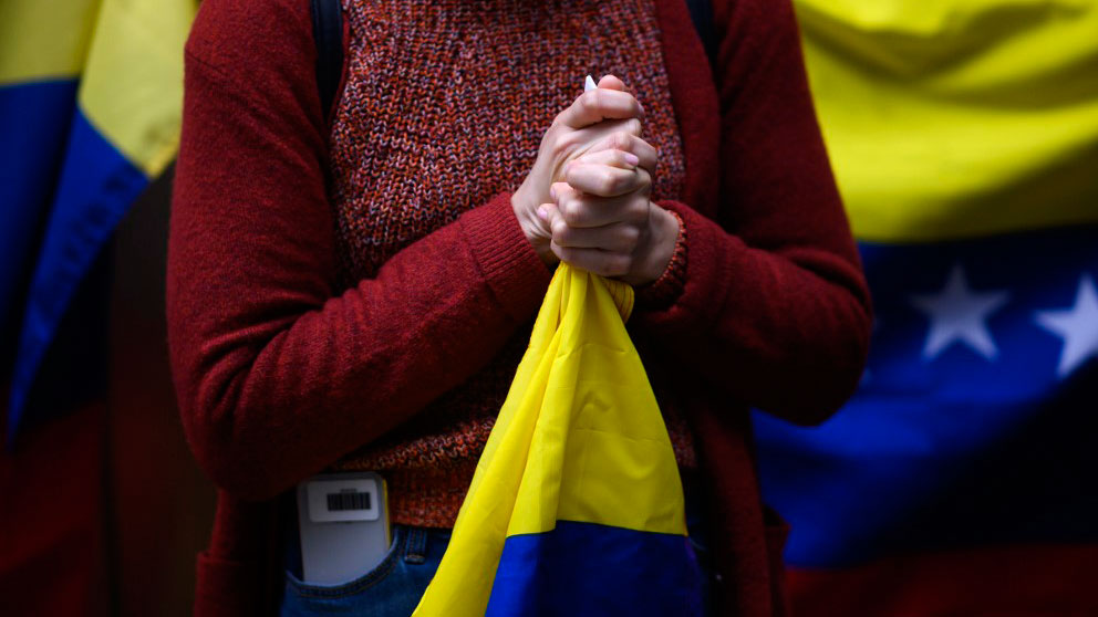 Una mujer sostiene entre sus manos una bandera de España. Foto: AFP