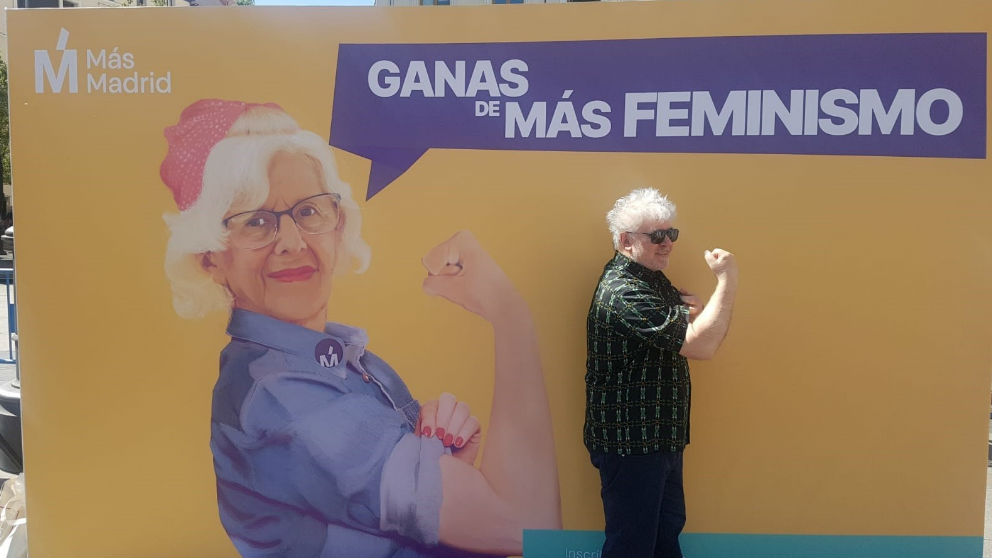 Almodóvar frente a un cartel de Más Madrid