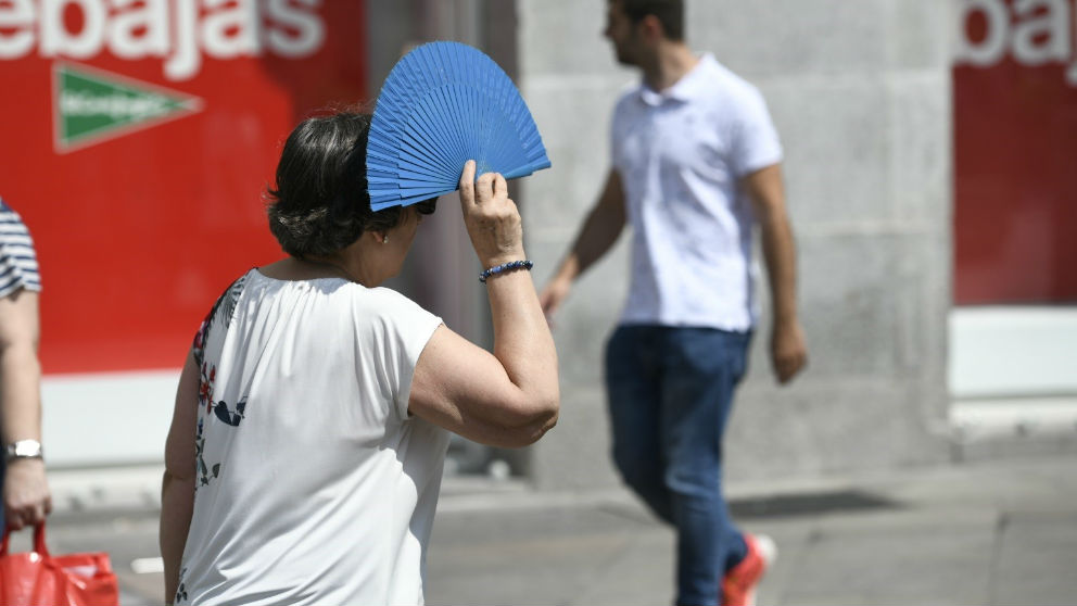 Una mujer se resguarda del sol con un abanico. Foto: Europa Press