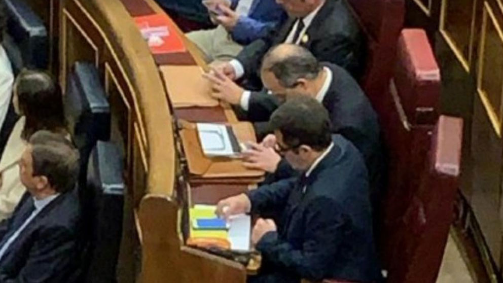 Jordi Turull y Jordi Sánchez usan sus teléfonos móviles aprovechando su ‘escapada’ de la cárcel al Congreso de los Diputados. Foto: Twitter