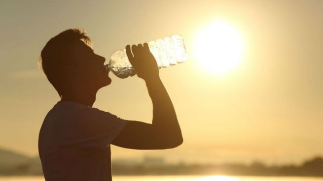 Un joven se hidrata bajo el sol
