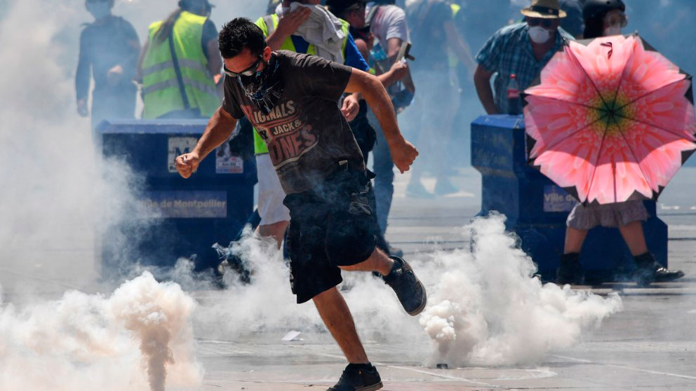 Un manifestante de los llamados «chalecos amarillos» devuelve a la Policía una bomba de gas lanzada para reprimir las violentas protestas. Foto: AFP