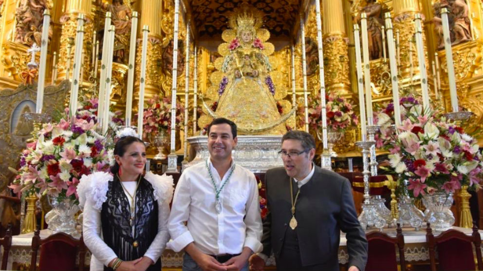 El presidente de la Junta de Andalucía, Juanma Moreno (c), delante de la Virgen del Rocío. (Foto: @JuanMa_Moreno)