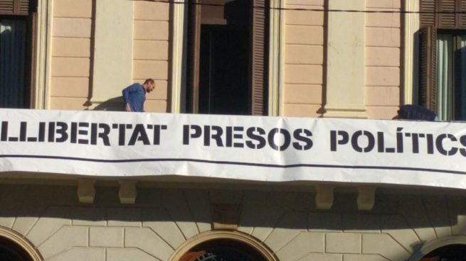 Un trabajador del ayuntamiento colocando la pancarta del ayuntamiento de Sabadell.