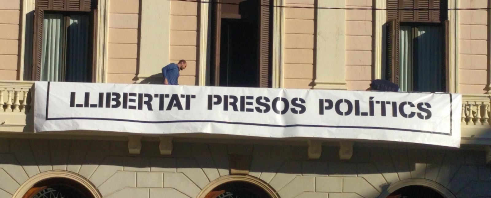 Un trabajador del ayuntamiento colocando la pancarta del ayuntamiento de Sabadell.