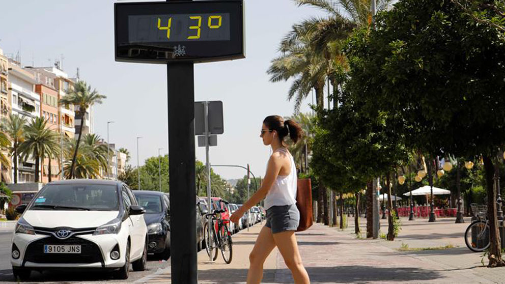 Una mujer camina junto a un termómetro que marca 43 grados en las calles de Córdoba (Foto: EFE).