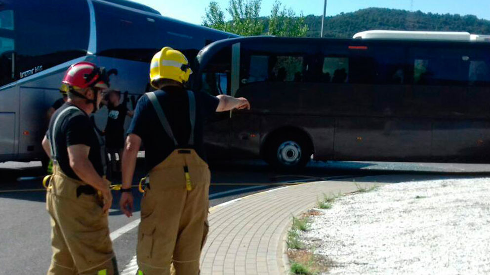 Dos bomberos junto a la zona de la provincia de Lérida donde han chocado los dos autobuses provocando cortes de tráfico.