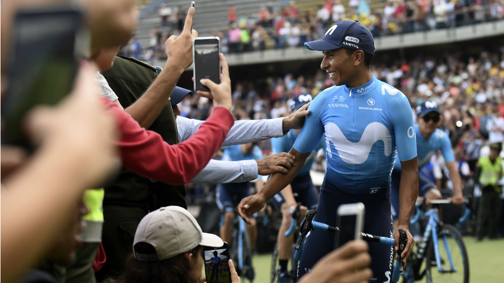 Nairo Quintana se hace fotografías con algunos aficionados en un estadio. (AFP)