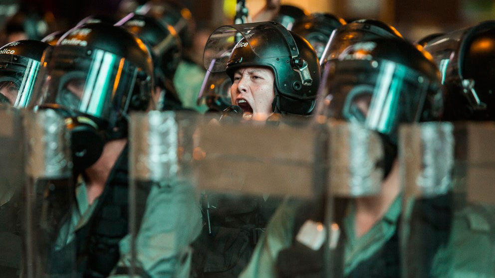 Un agente de las fueras del orden de China da órdenes a sus hombres para sofocar las protestas celebradas en Hong Kong. Foto: AFP