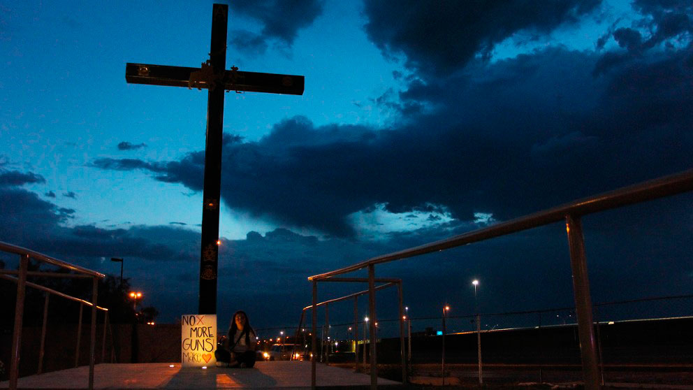 Una joven sostiene una pancarta contra las armas junto a una gran cruz en Ciudad Juárez, localidad cercana a El Paso, donde 20 personas perdieron la vida en un tiroteo en una tienda Walmart. Foto: AFP