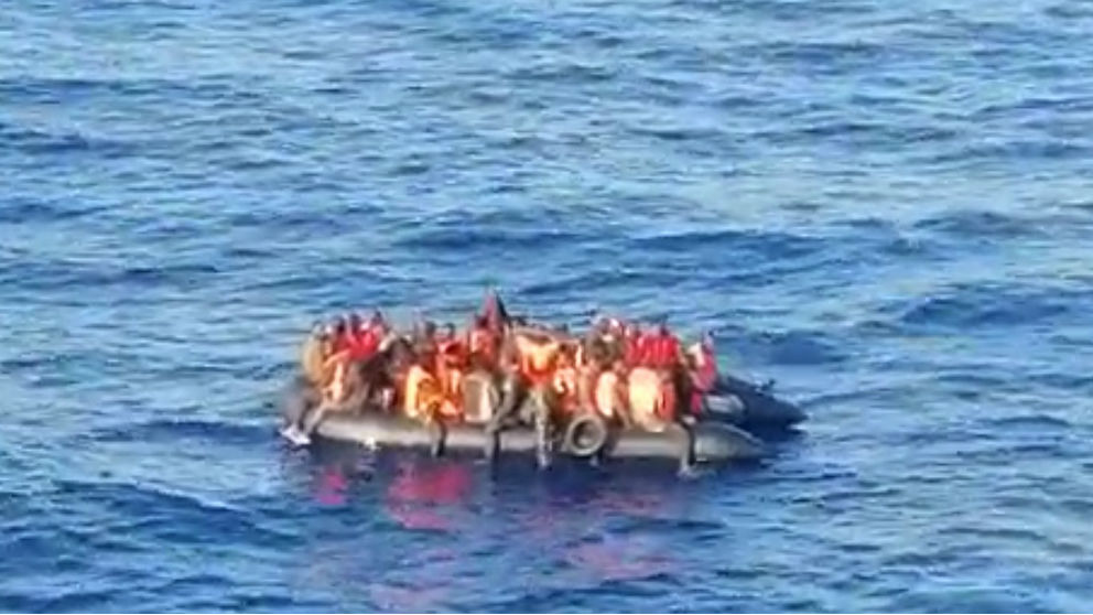Una patera con inmigrantes a bordo fotografiada desde un barco.
