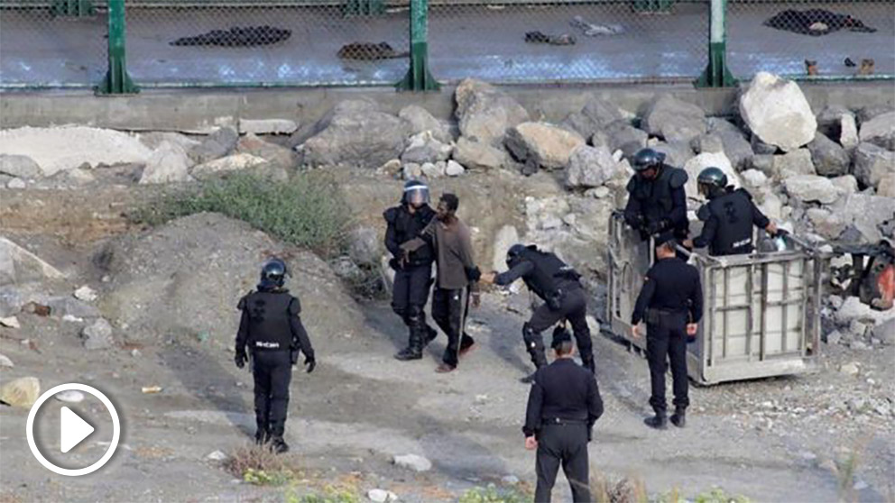 Agentes del GRS de la Guardia Civil detienen a algunos de los inmigrantes que asaltaron la valla de Ceuta.